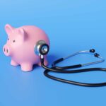 Black stethoscope on the body of a pink piggy bank